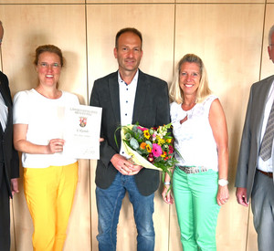 Gruppenbild mit 5 Menschen und Blumenstrauß.