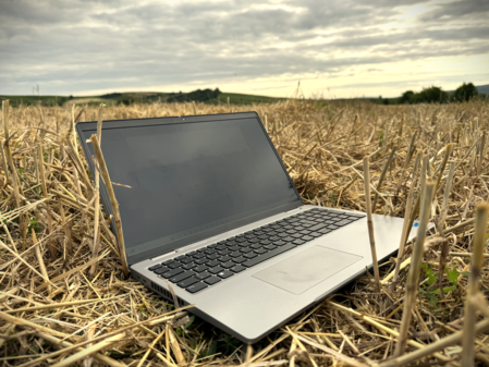 Laptop liegt auf einem Stoppelacker.