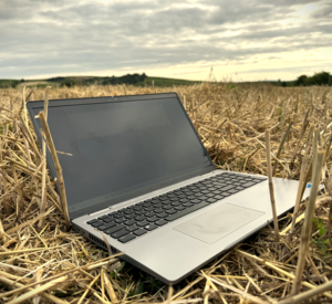 Laptop liegt auf einem Stoppelacker.